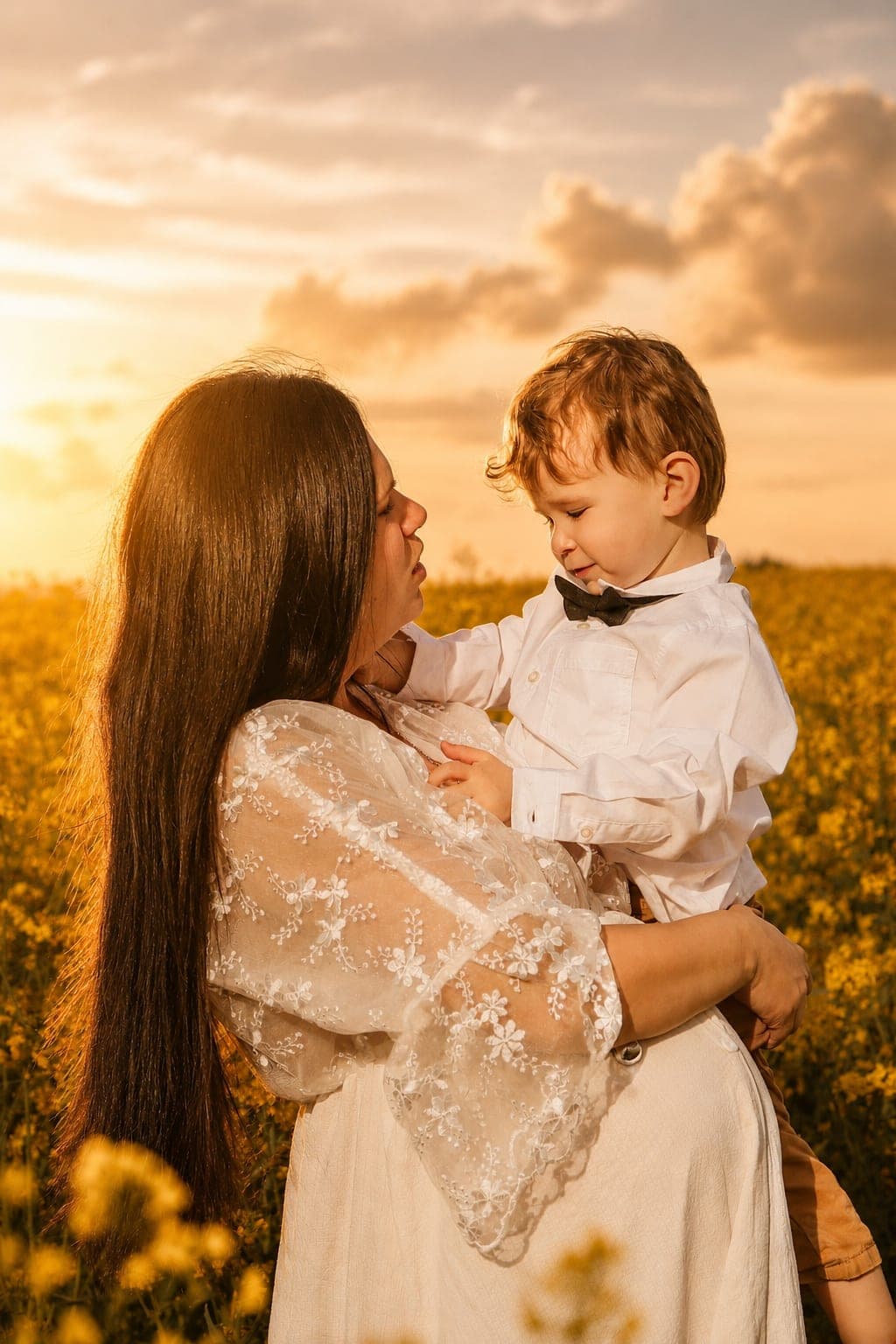Une maman et son petit garçon front contre front, dans un champ au soleil couchant.