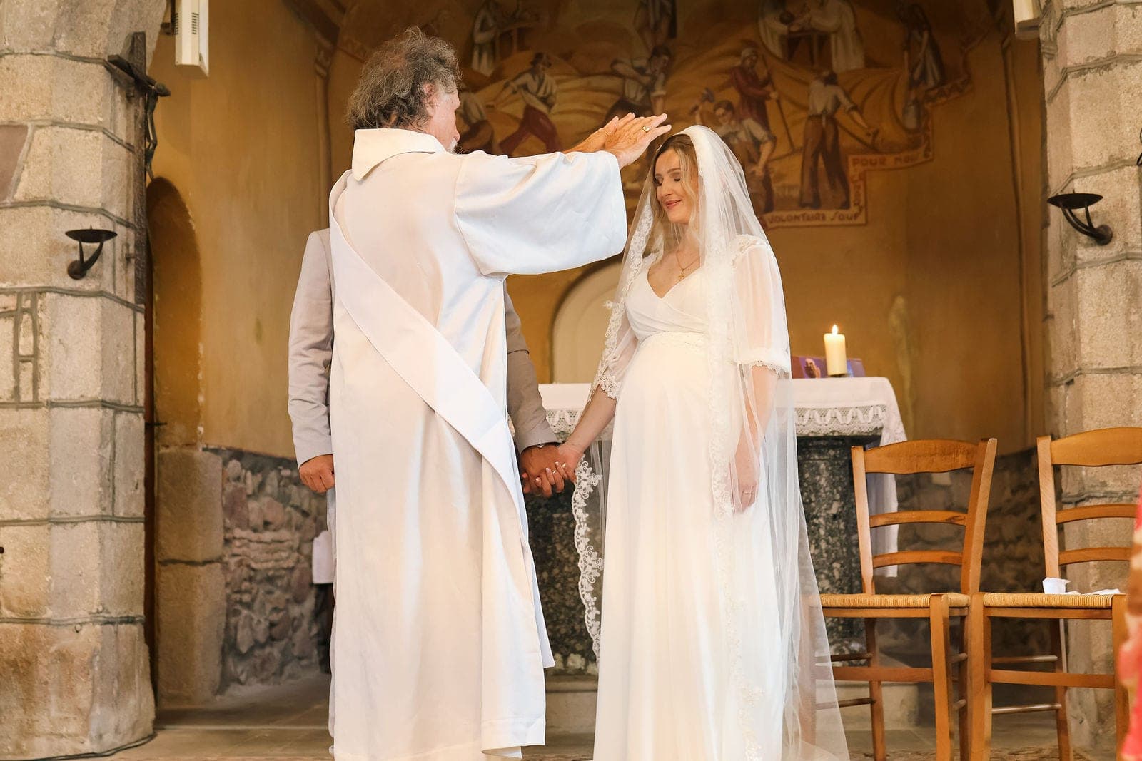 La bénédiction des mariés par le prêtre, dans la chapelle.