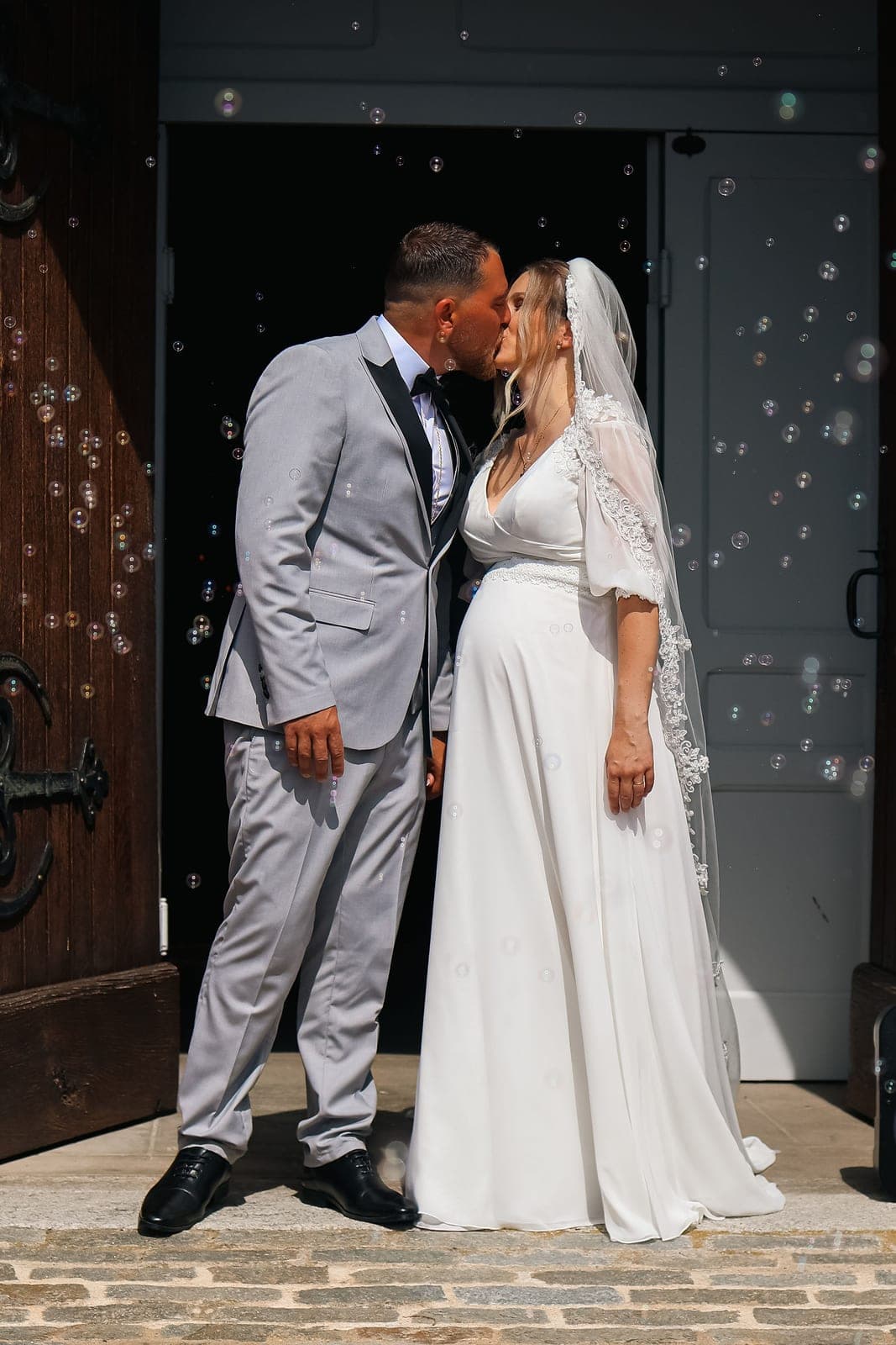 Un baiser sous les bulles de savon, sur le pas de la porte de l’église.