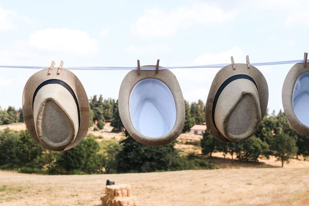 Des chapeaux de paille suspendus à un fil, à disposition des invités.