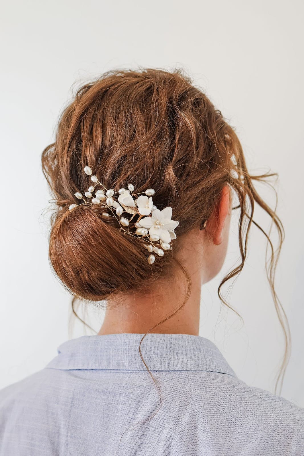 Le chignon de la mariée, piqué de fleurs nacrées.