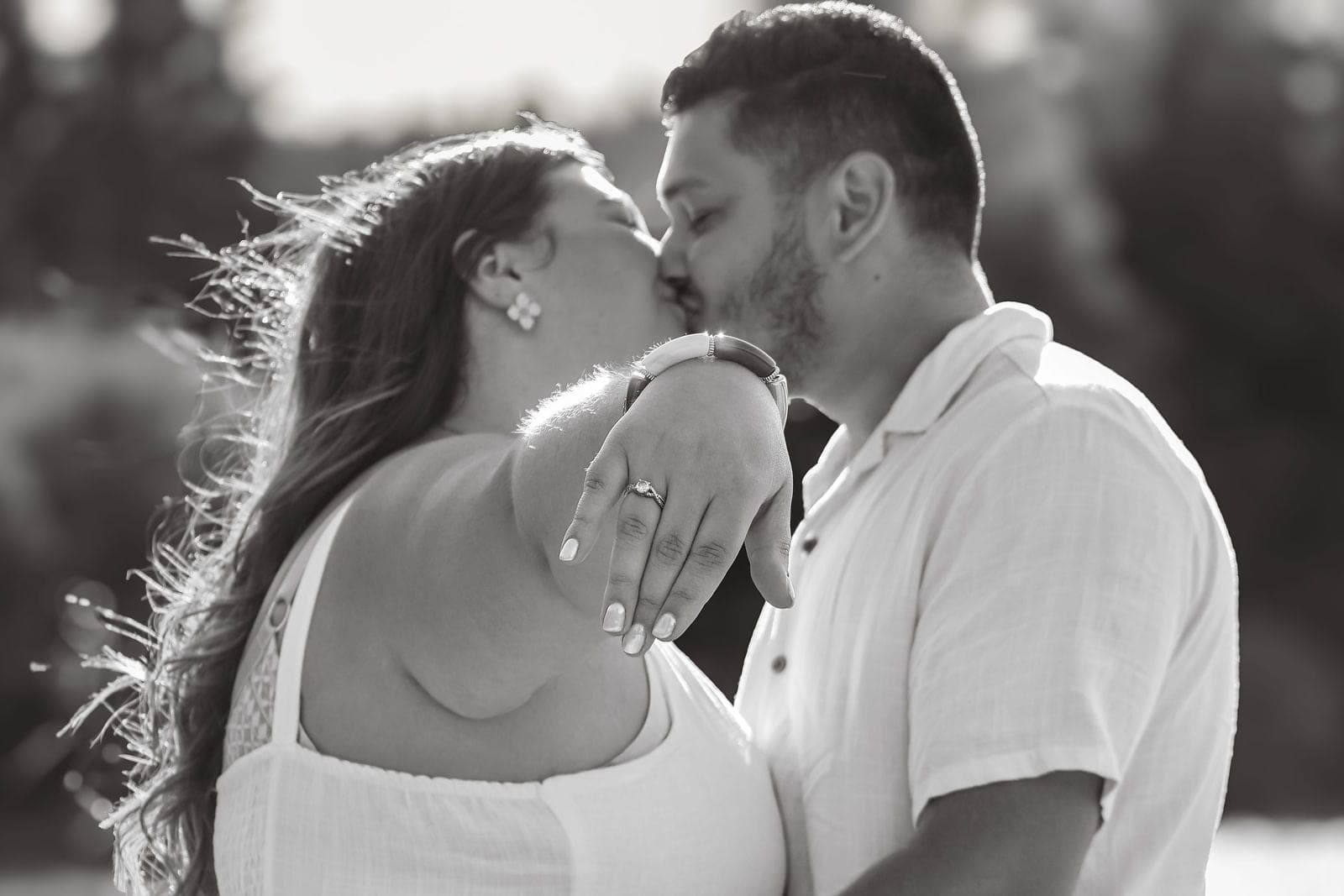 En noir et blanc, un baiser et la bague de fiançailles en avant.
