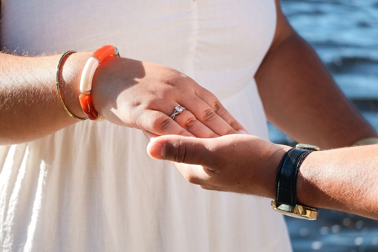 Les deux mains réunies, la bague de fiançailles au premier plan.