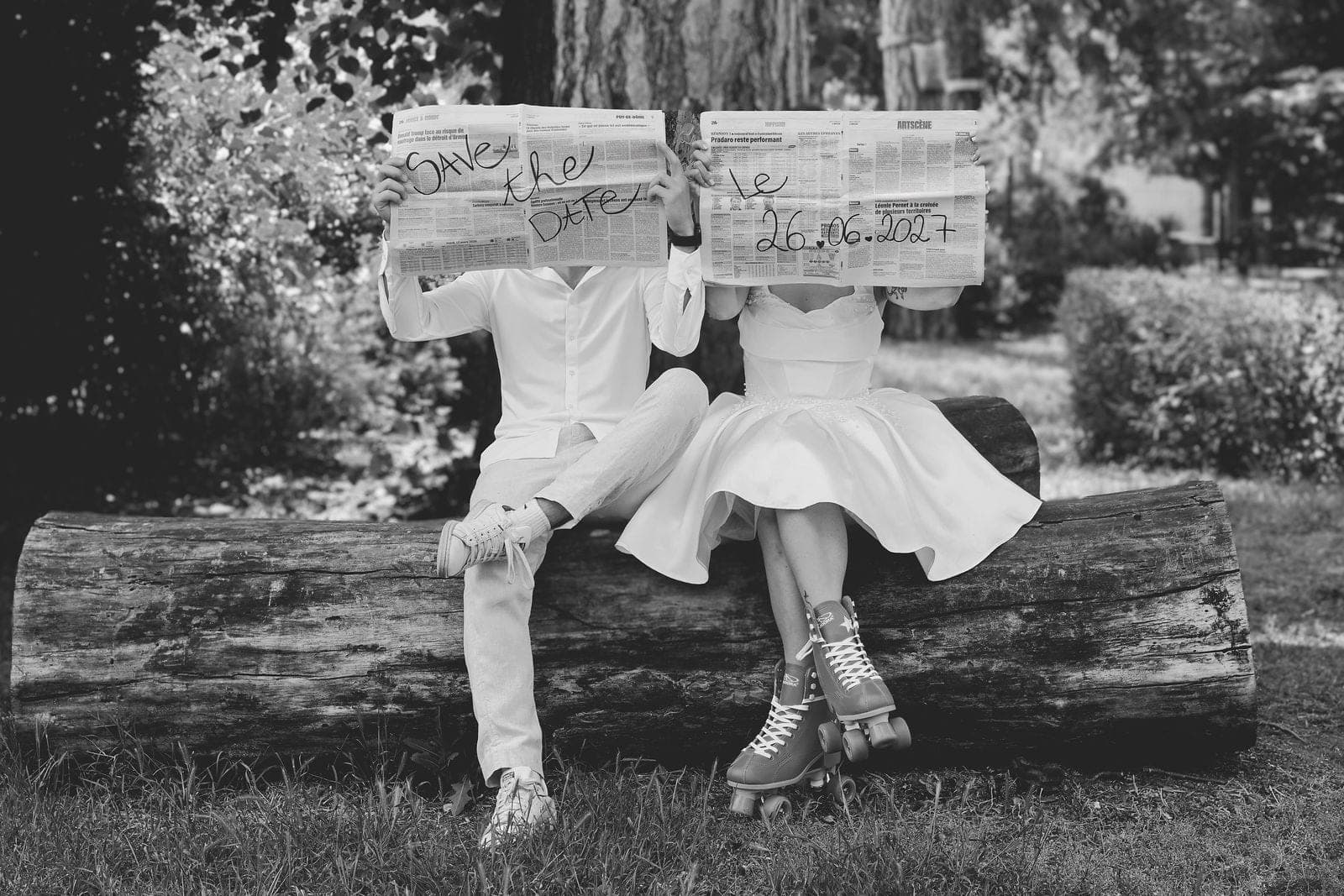En noir et blanc, le couple cache son visage derrière un « Save the date » écrit à la main.
