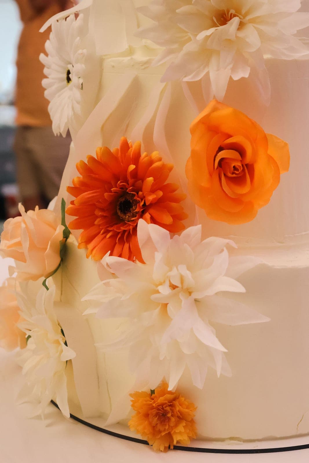 Le gâteau de mariage, orné de gerberas orange et de fleurs blanches.