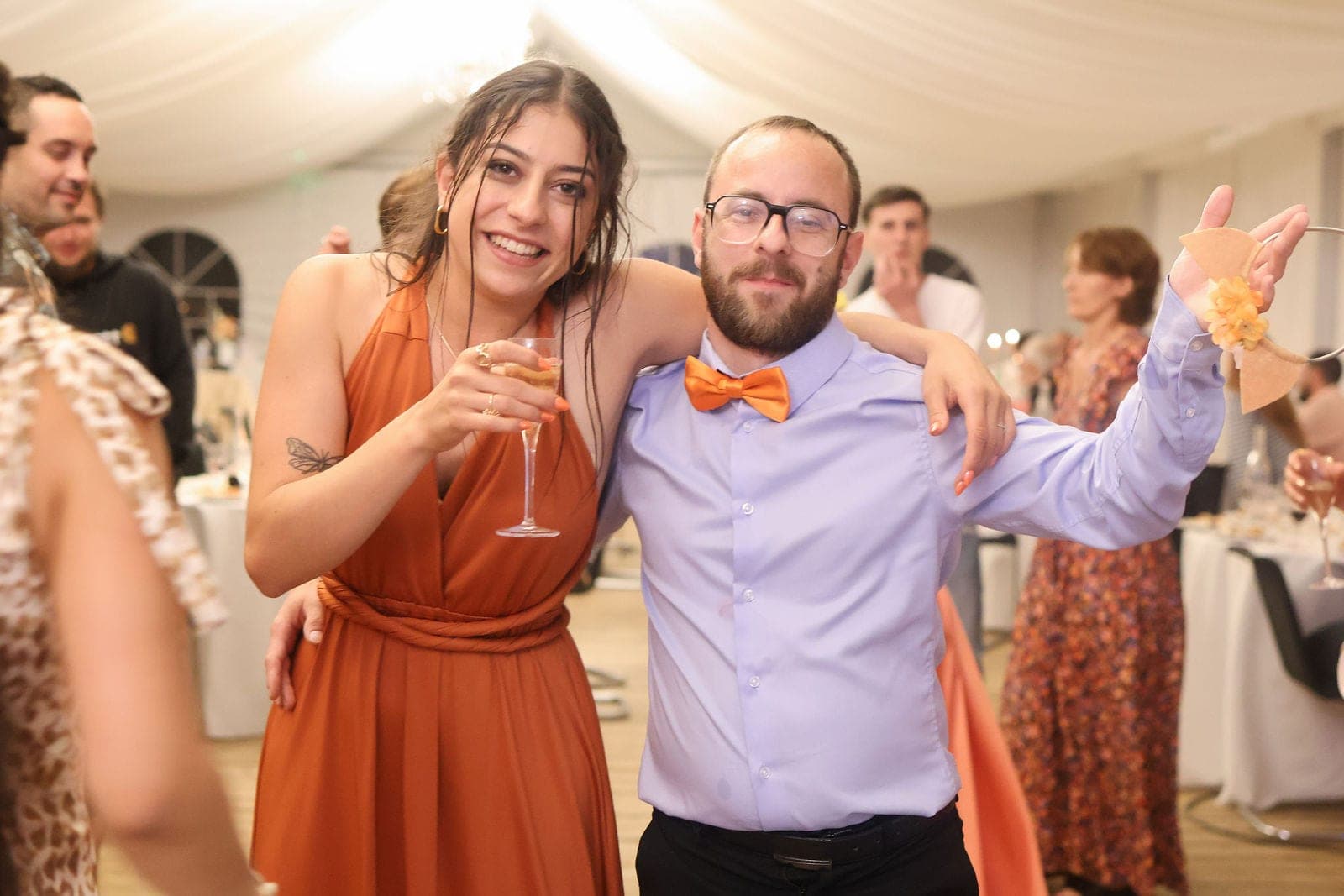 Deux invités trinquent en pleine soirée, coupe à la main.