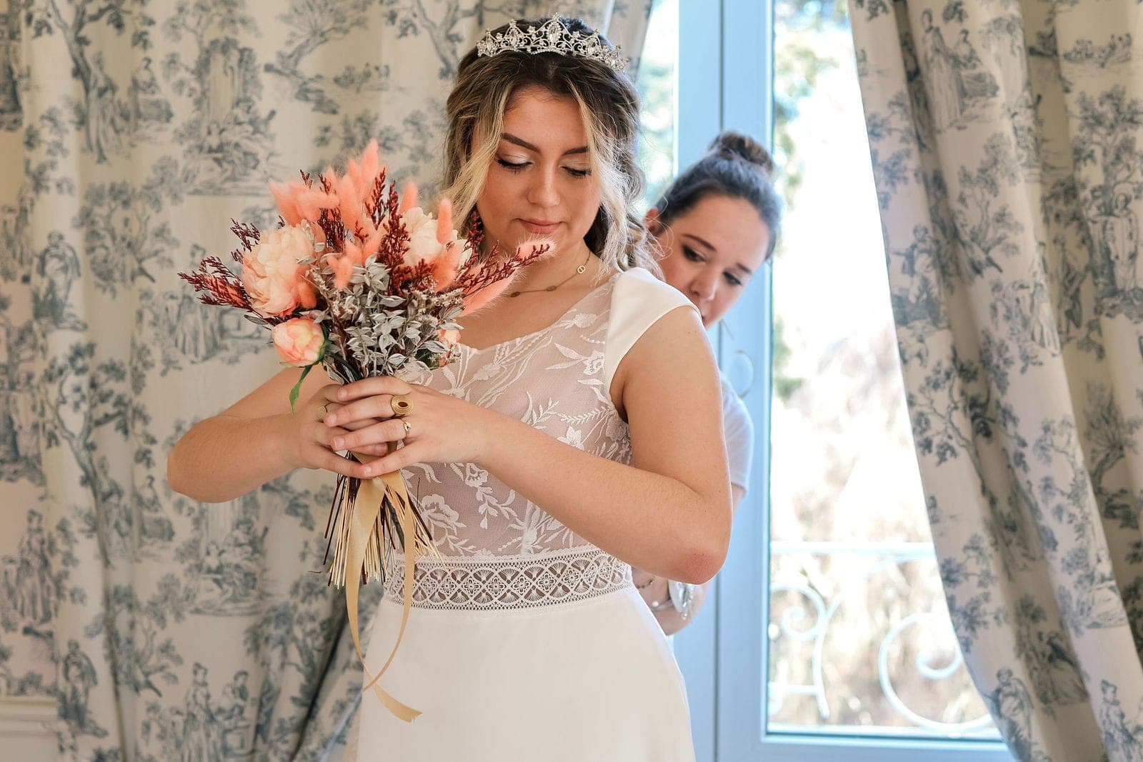 La mariée découvre son bouquet de fleurs séchées, couronne dans les cheveux.