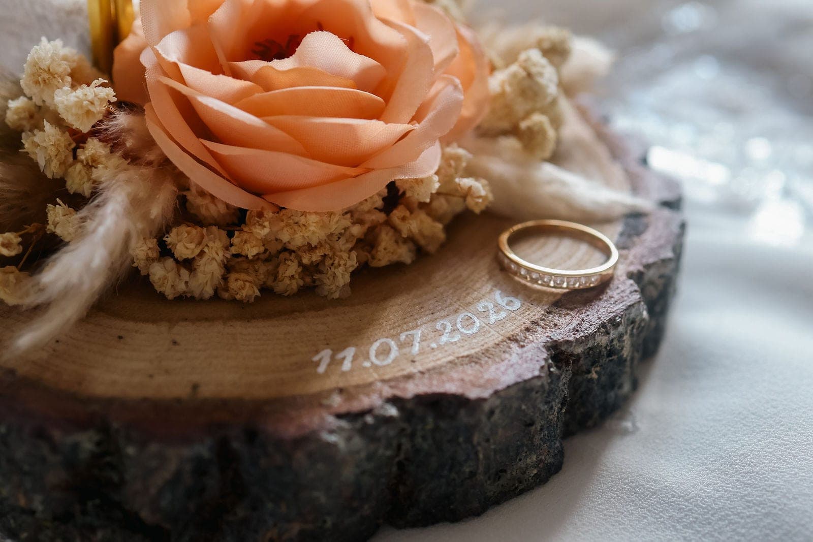 Les alliances posées sur une rondelle de bois gravée à la date du mariage.