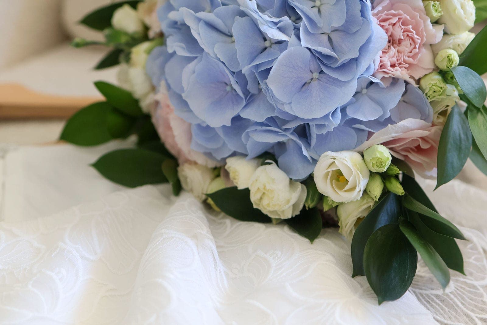 Le bouquet posé sur la robe : hortensias bleus et roses blanches.