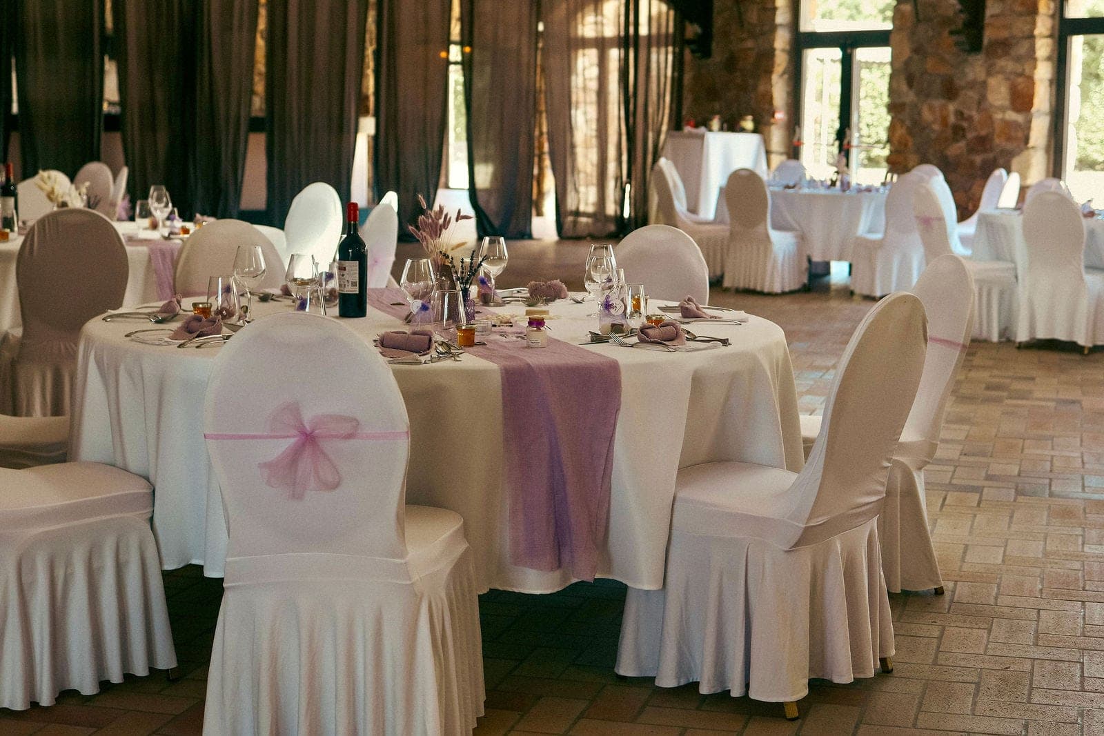 Les housses de chaises nouées de rose, autour des tables rondes.