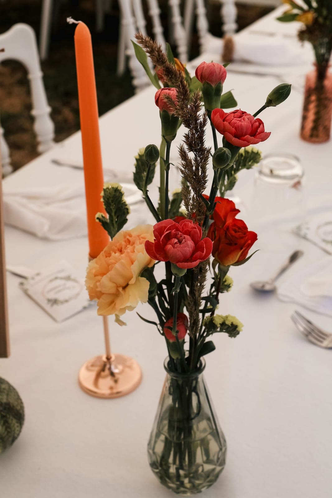 Pivoines corail et bougies orange, au centre de la tablée.