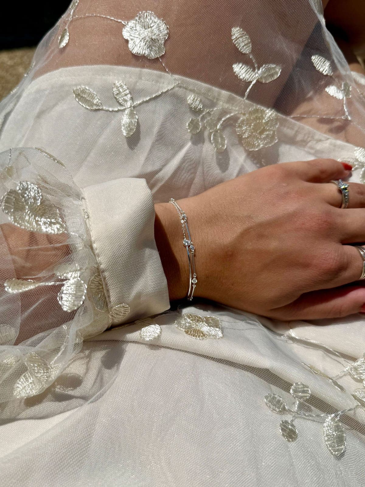 Un bracelet fin porté sur une manche brodée.