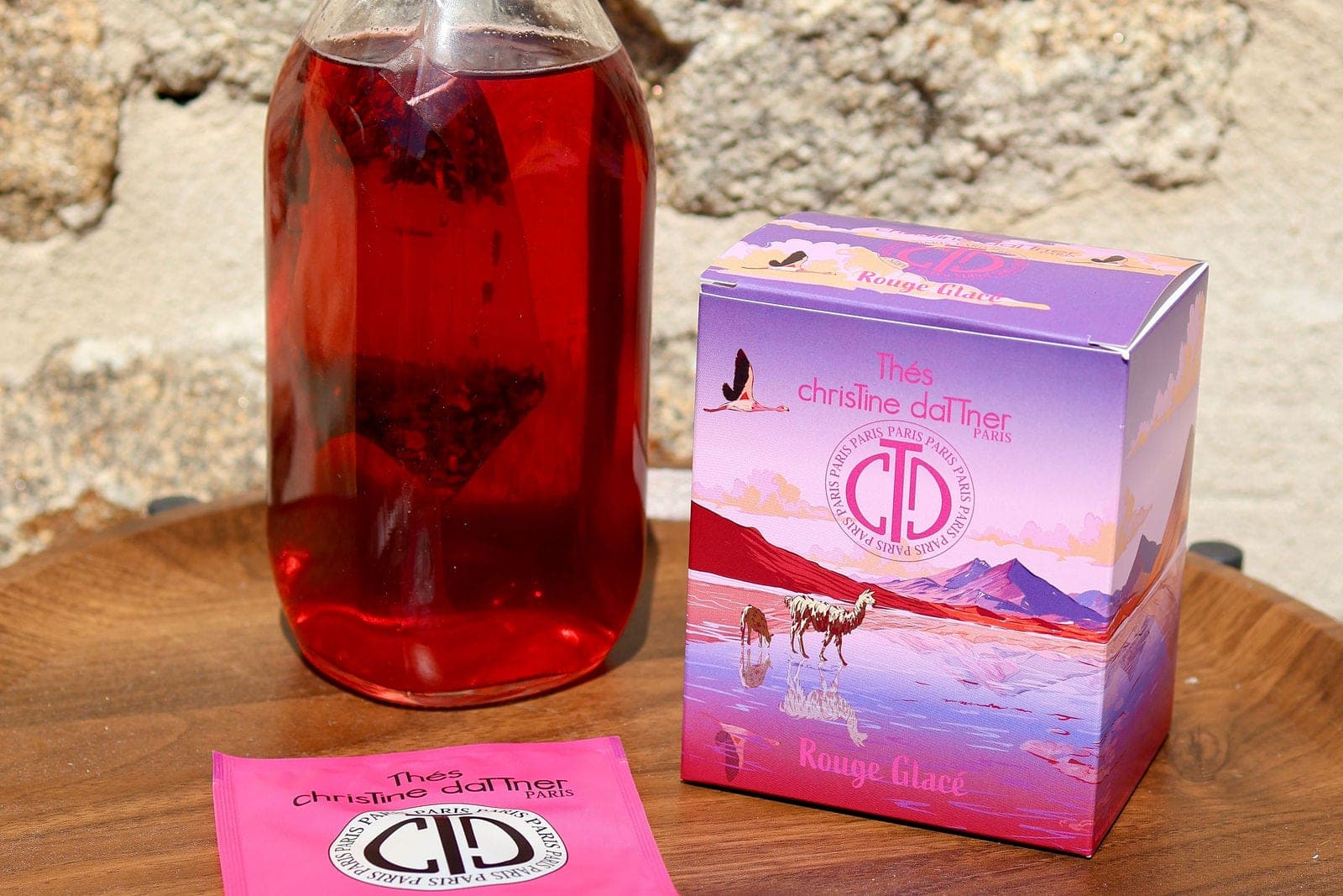 Un thé glacé rouge servi en carafe, à côté de son coffret.