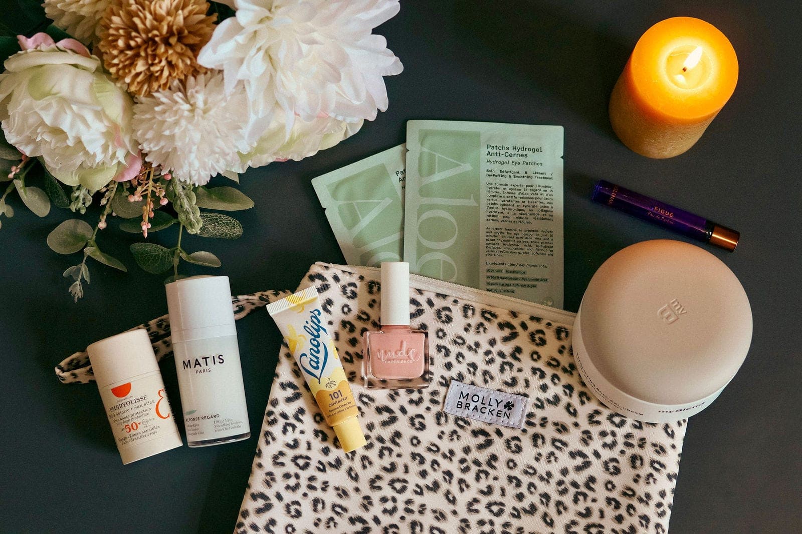 Une trousse de soins ouverte, produits et fleurs disposés autour.