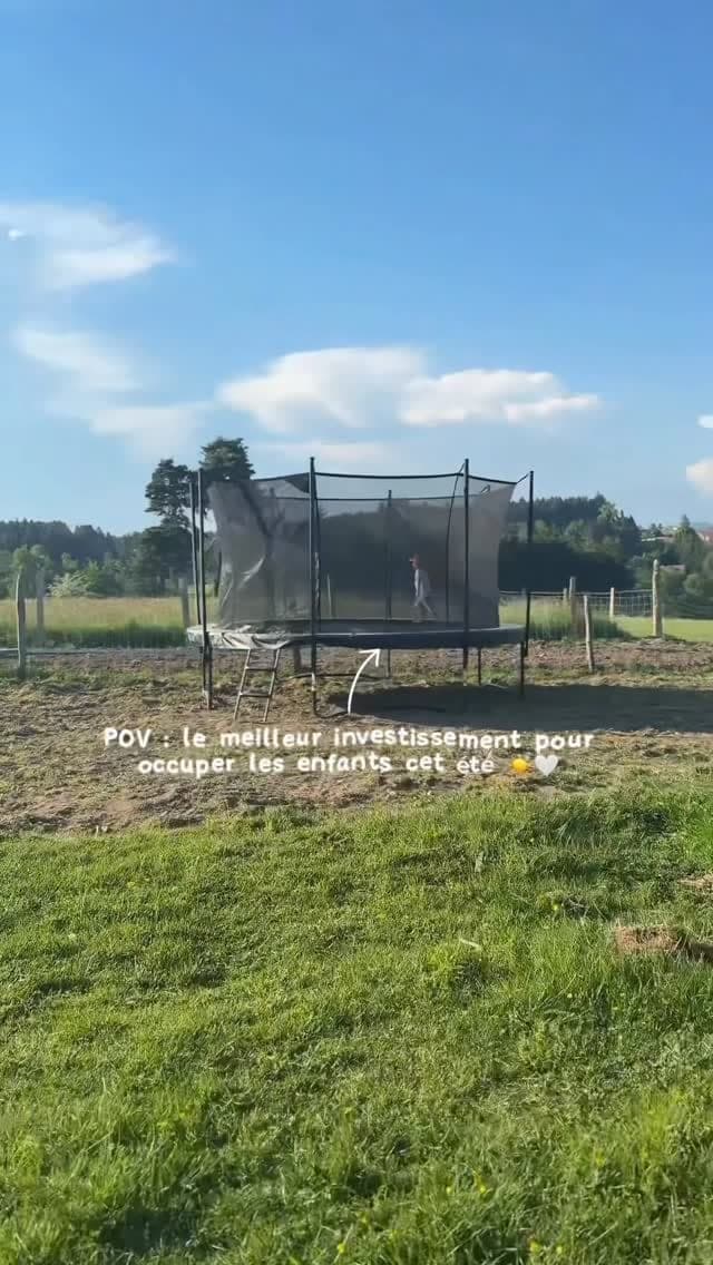 Un trampoline monté dans un pré, sous un grand ciel d’été.