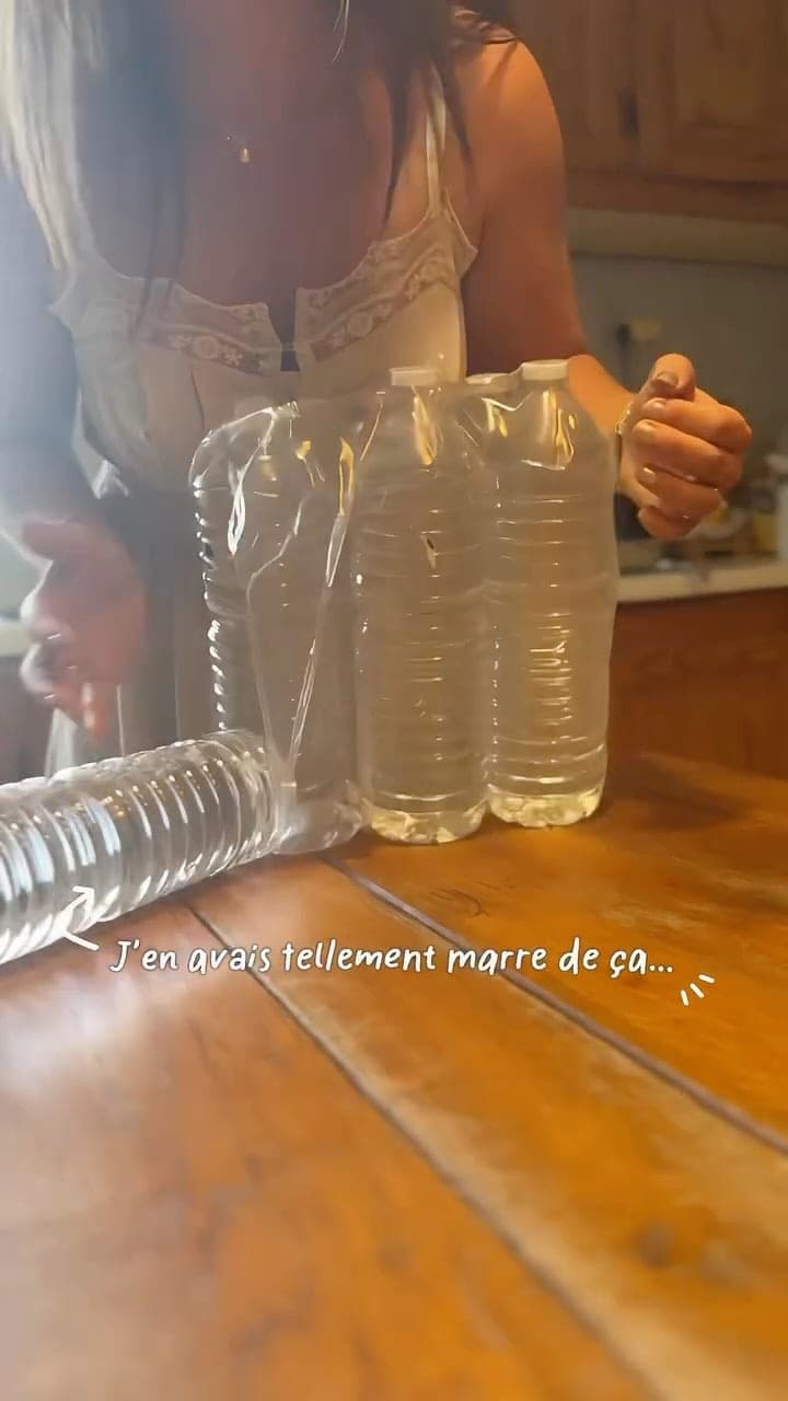 Des bouteilles d’eau en plastique alignées sur une table en bois.