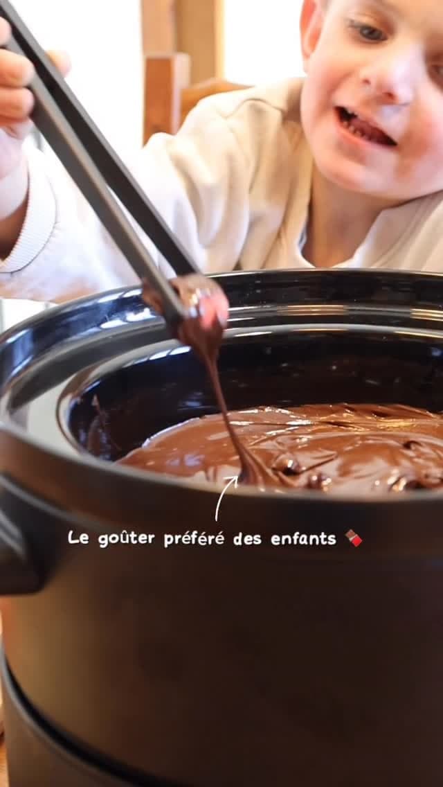 Un enfant plonge une pique dans la casserole de chocolat fondu.