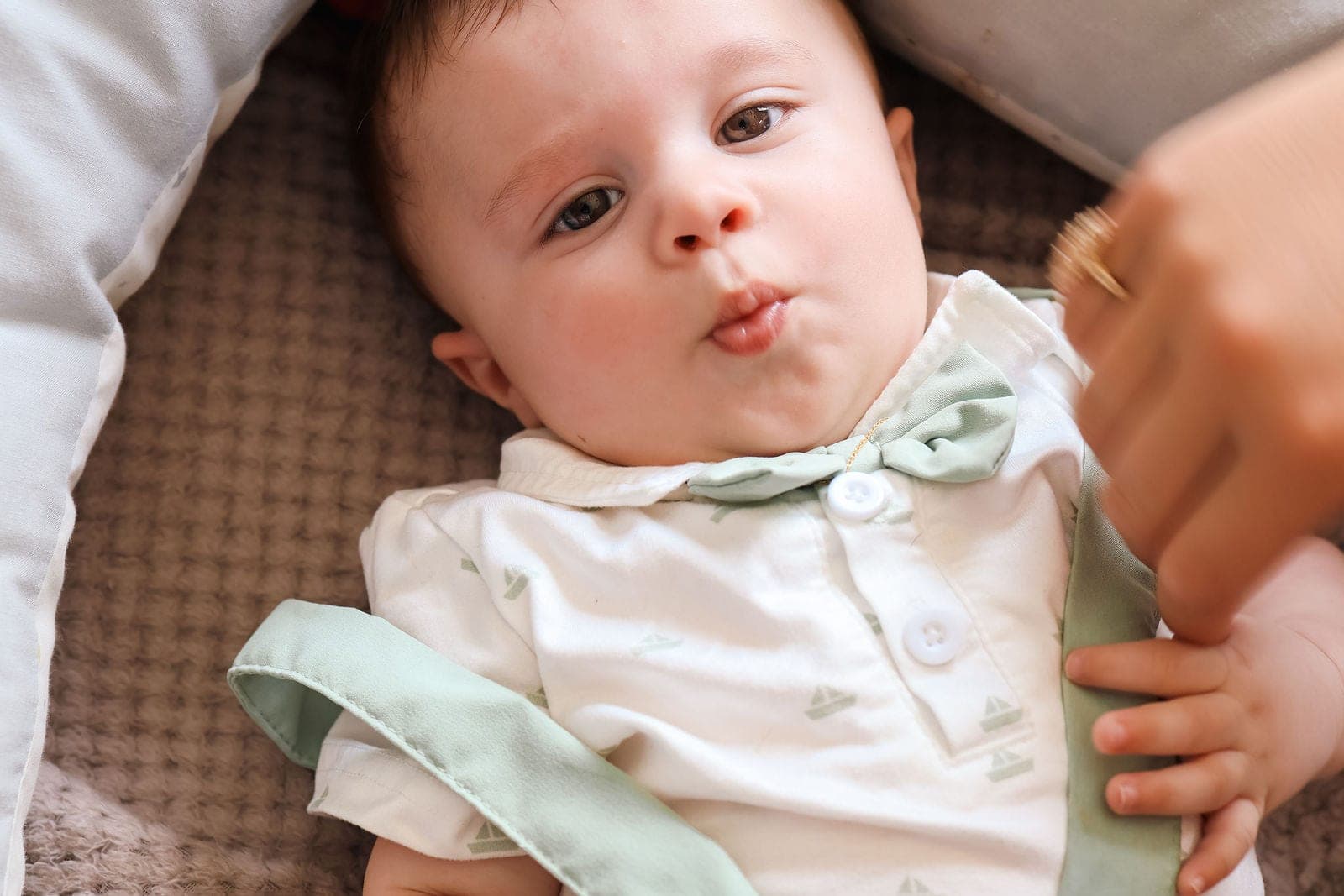 Bébé de quelques mois, en chemise blanche et nœud vert d’eau, tout juste réveillé.