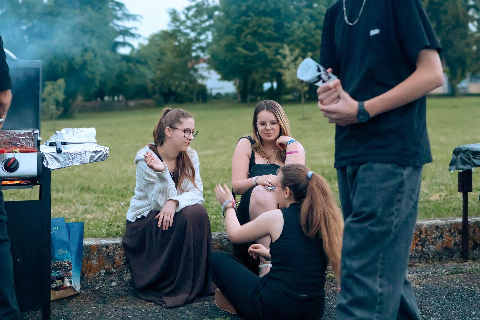 Un groupe d’amis assis dans l’herbe, à la fin du repas.
