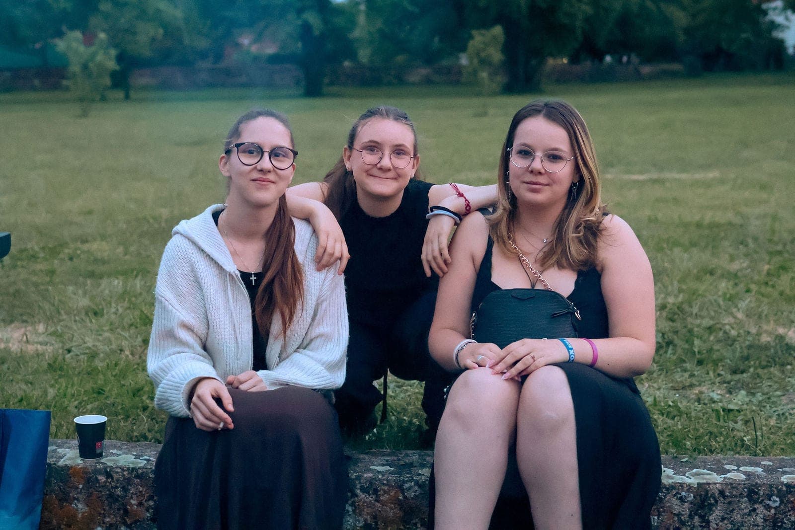 Trois amies posent ensemble sur un muret.