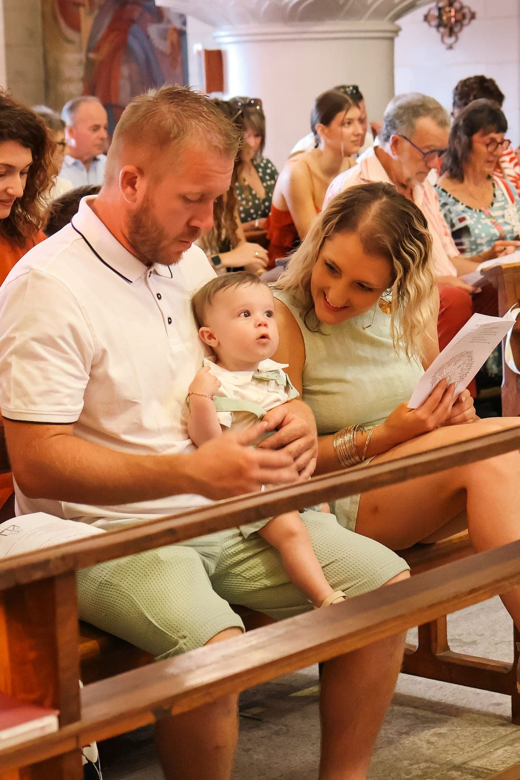 Les parents et leur bébé sur le banc de l’église, pendant la célébration.