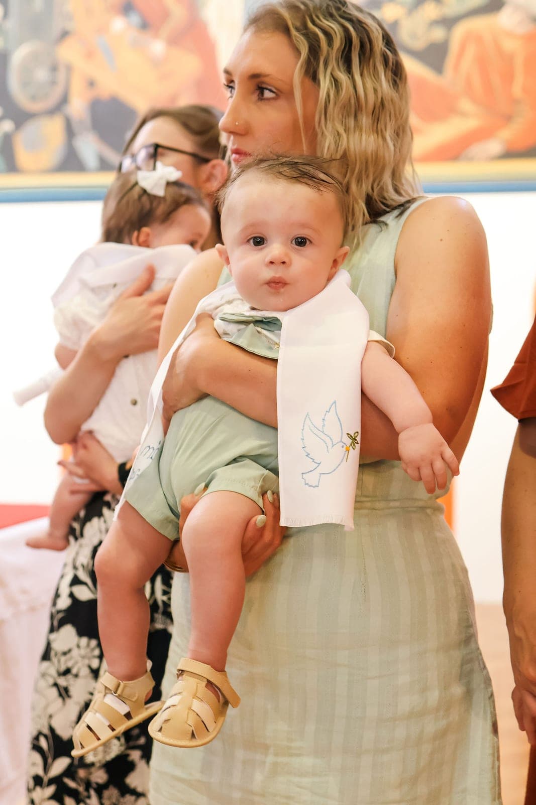Bébé dans les bras, l’étole blanche posée sur lui.