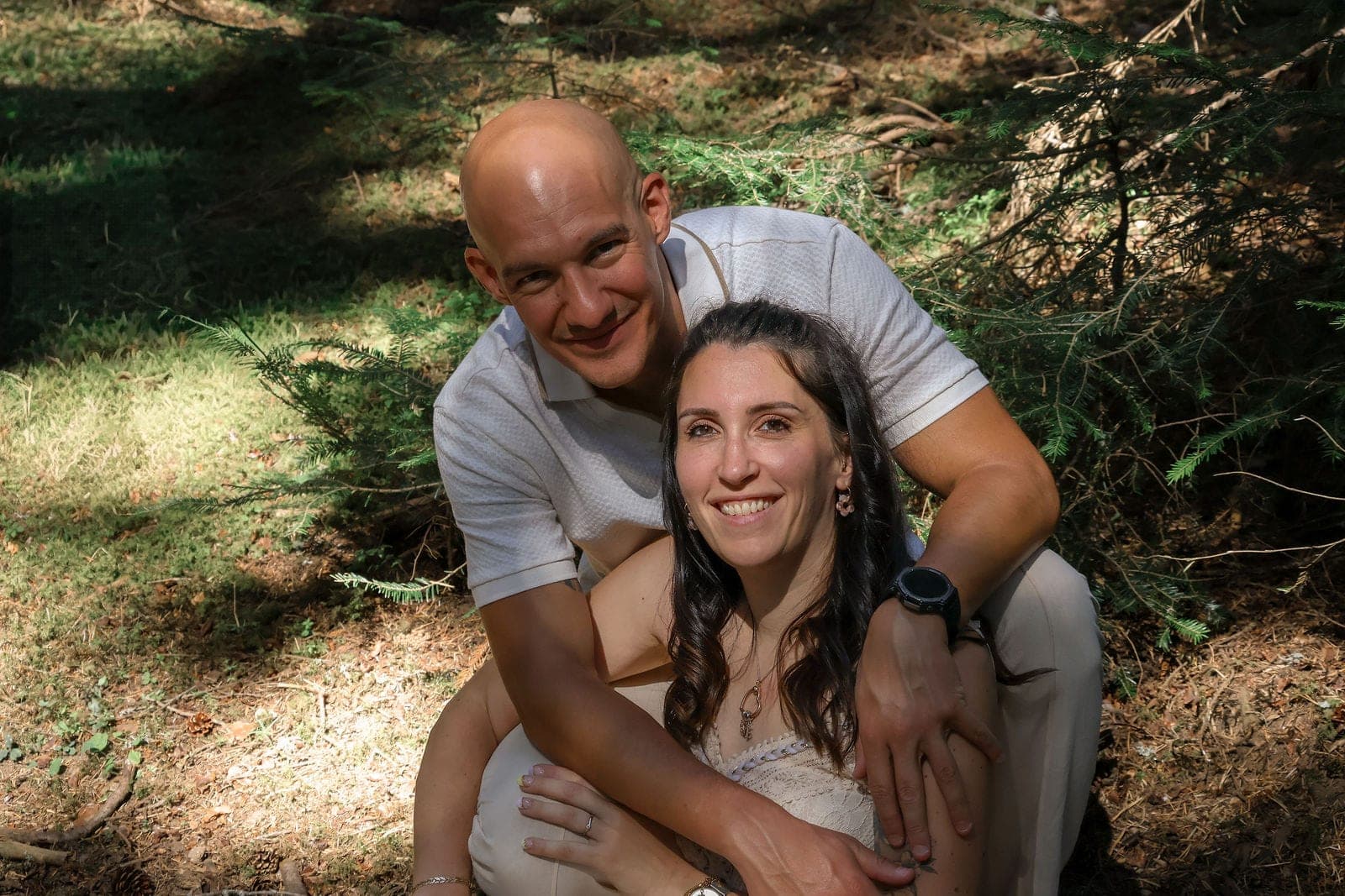 Un couple complice dans le sous-bois, sourire à l’objectif.
