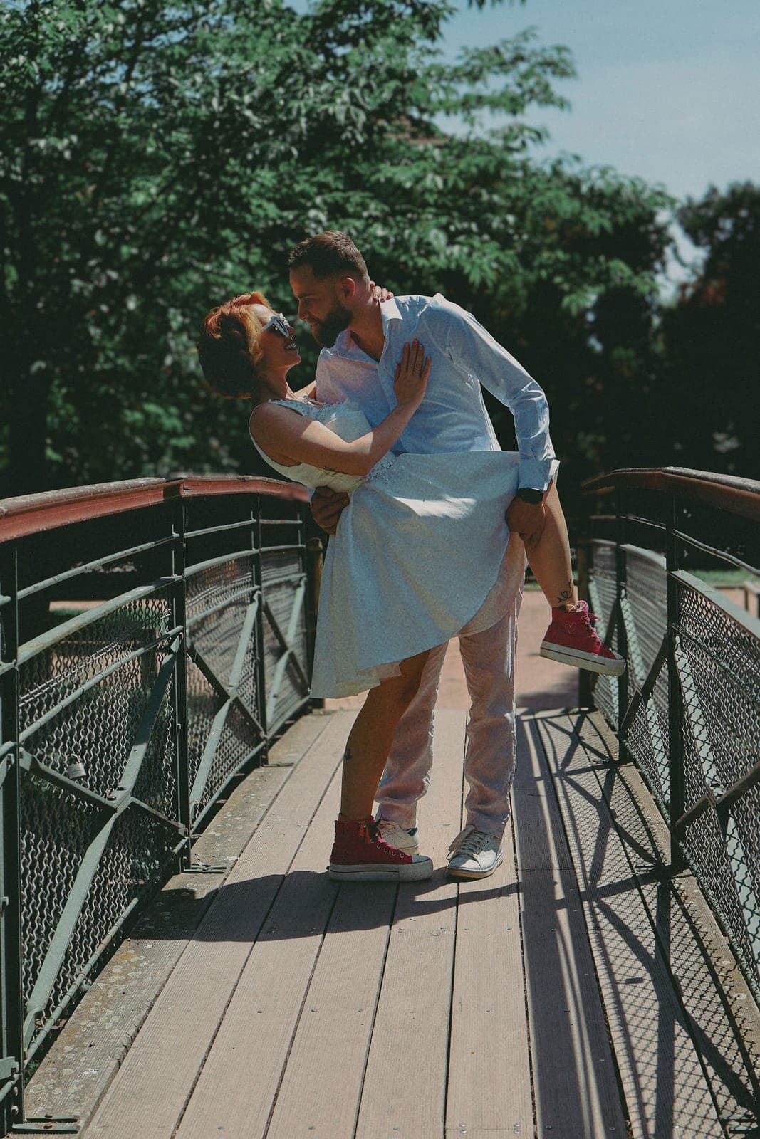 Il la soulève sur la passerelle, robe bleue au vent.