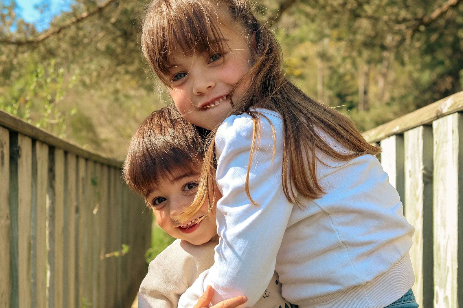 Un frère et une sœur joue contre joue, tout sourire.