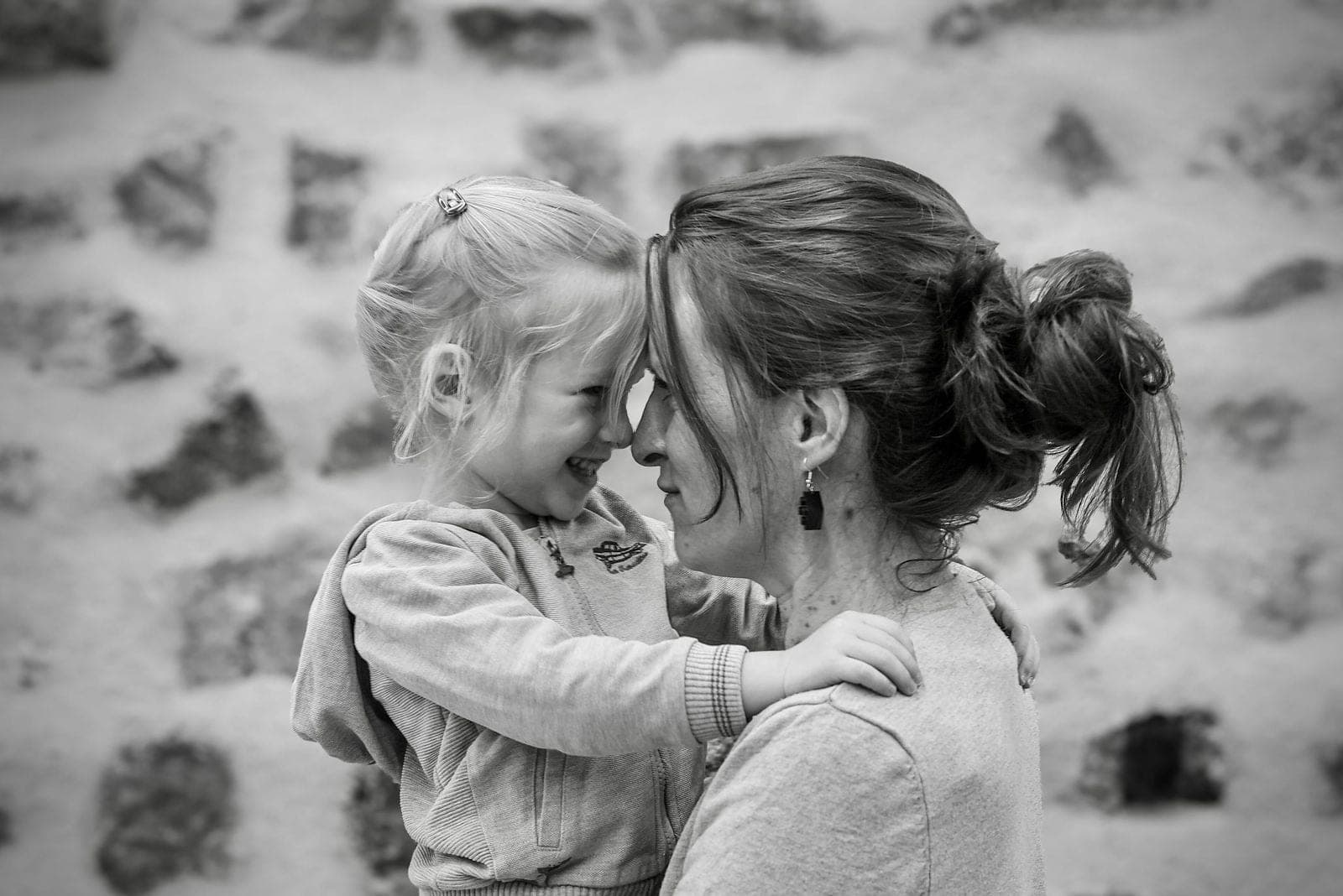Une maman et sa fille front contre front, en noir et blanc.