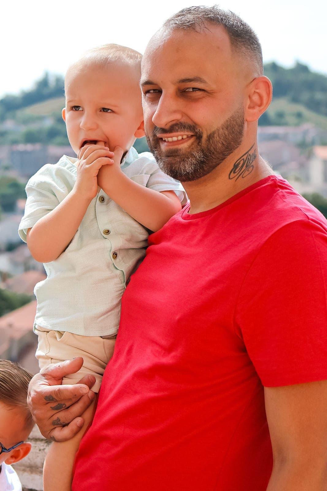 Un papa porte son petit garçon dans les bras, la vallée en contrebas.