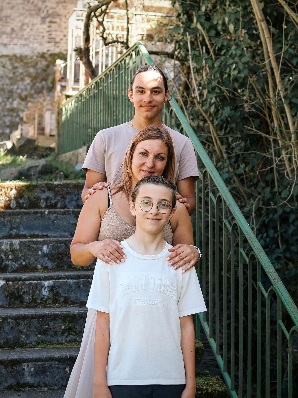 Une famille de quatre sur l’escalier de pierre, les mains posées sur les épaules du plus grand.