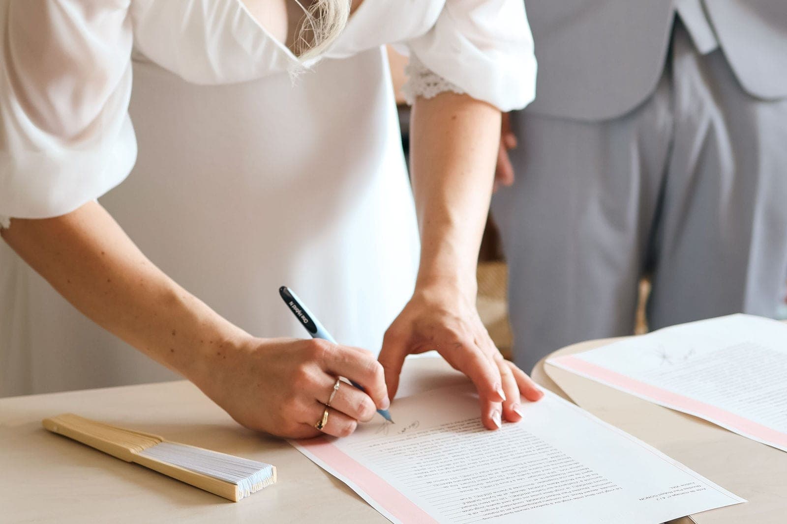 La mariée signe le registre, le marié juste à côté d’elle.