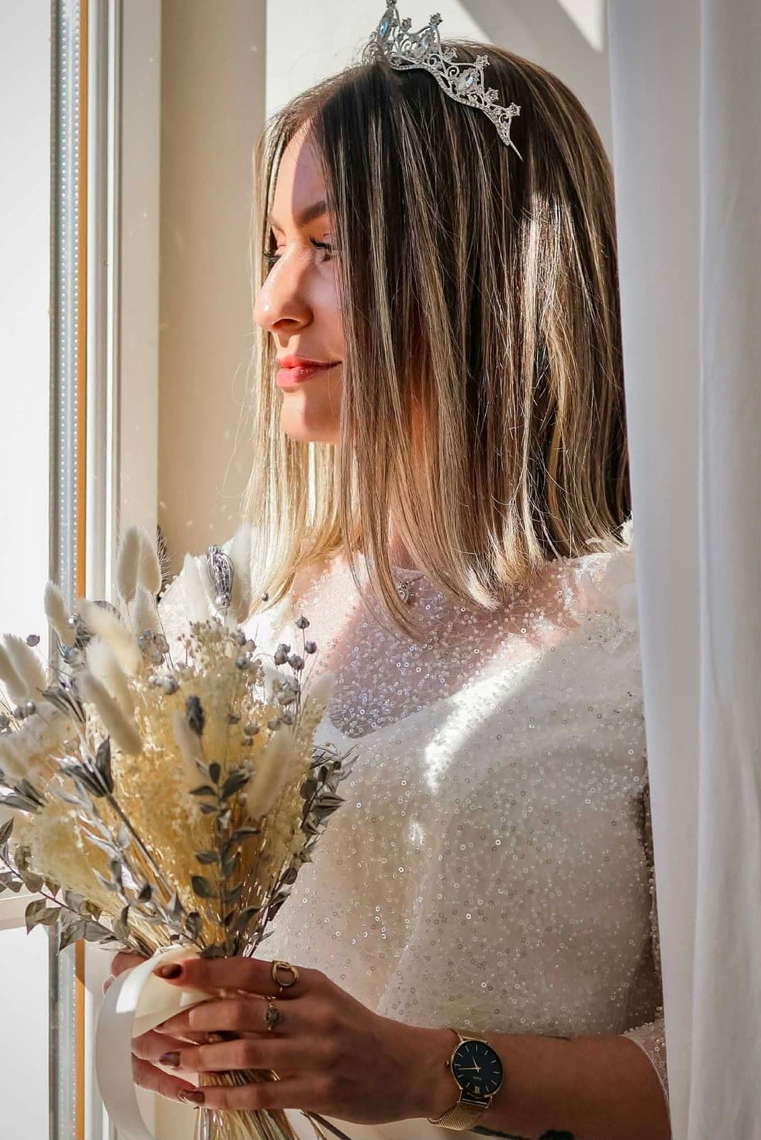 La mariée en diadème, son bouquet de fleurs séchées entre les mains.