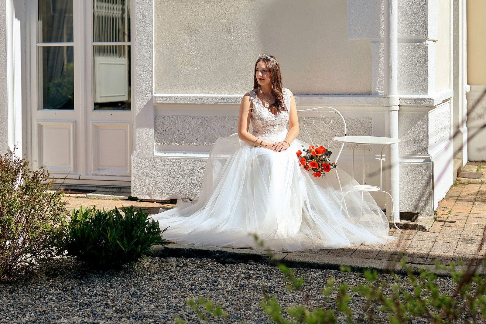 La mariée assise sous le porche, sa longue traîne étalée sur les marches.