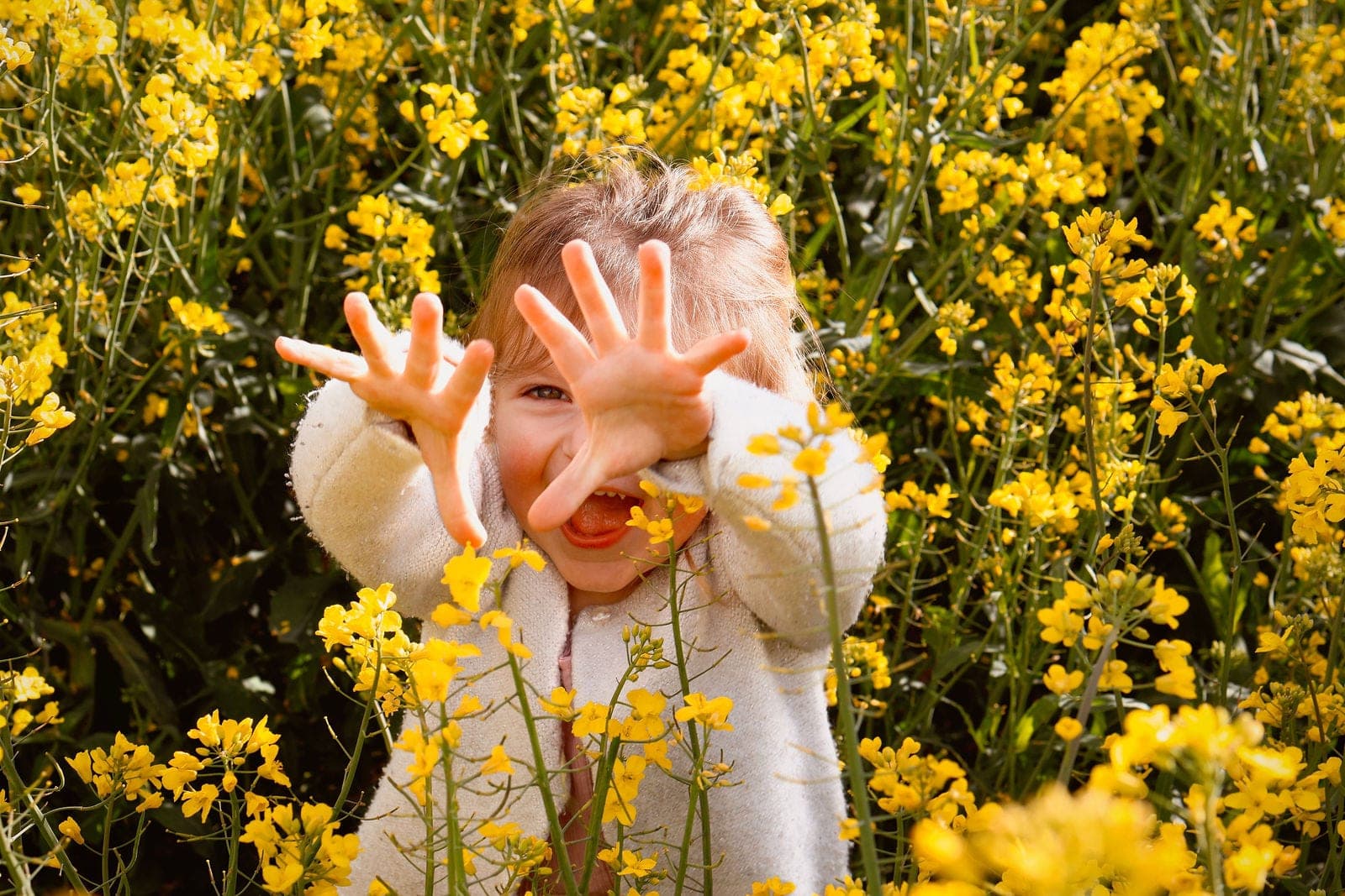 Les mains tendues vers l’objectif au milieu des fleurs jaunes, en plein fou rire.