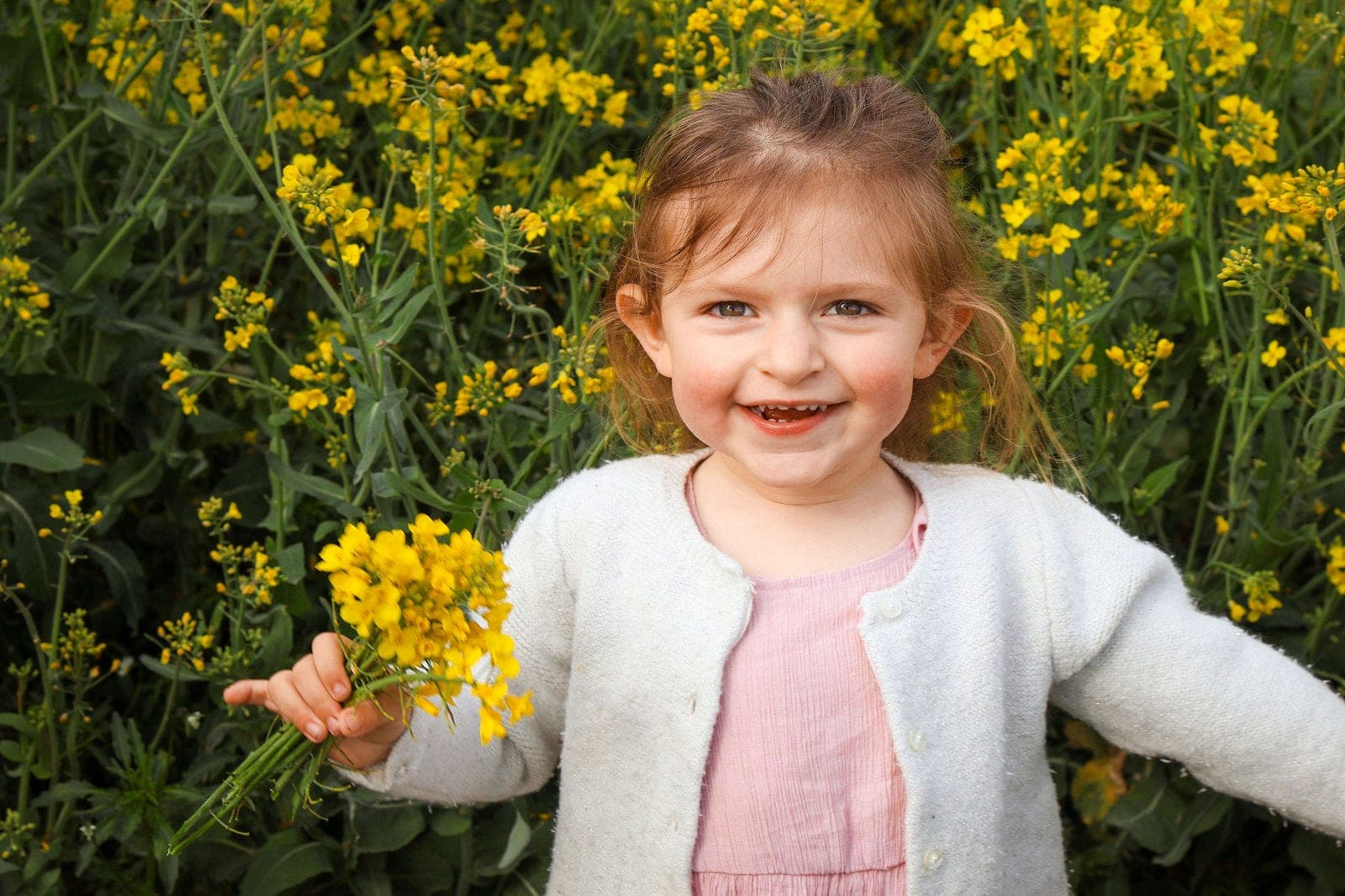 Un bouquet de fleurs jaunes à la main et un grand sourire.