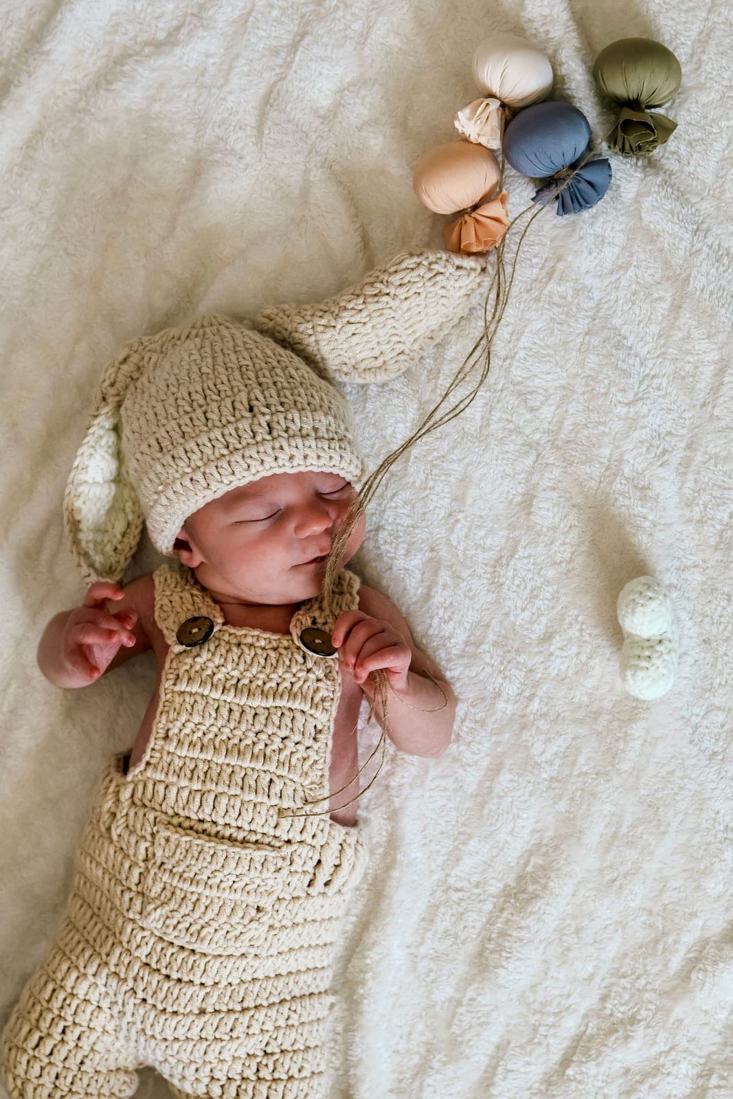 Bébé endormi dans sa tenue de laine, poings fermés.