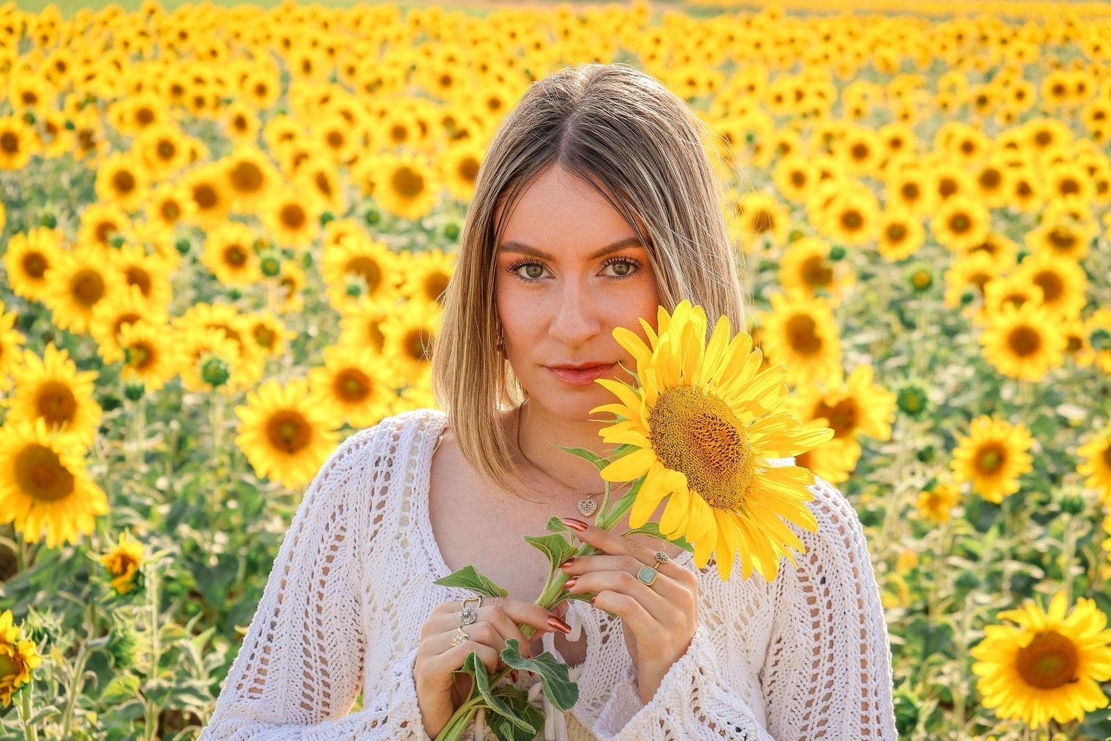 Un tournesol à la main, au milieu du champ.