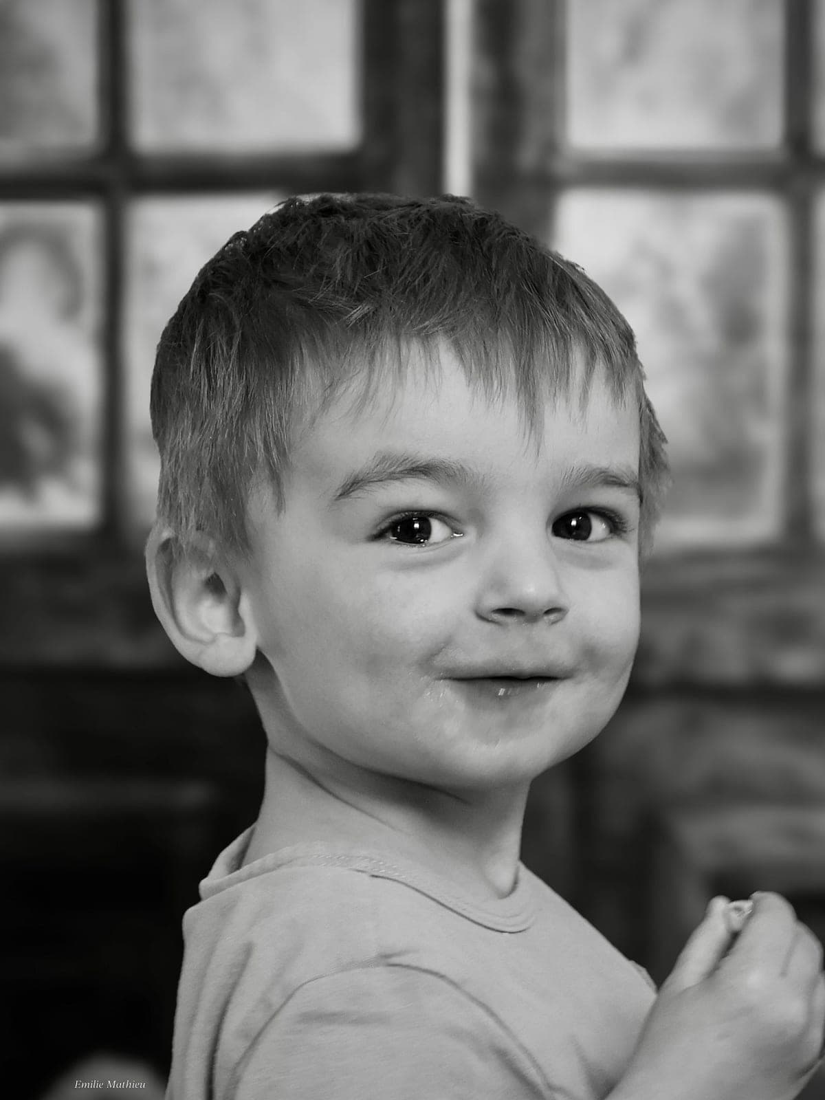 Portrait en noir et blanc d’un petit garçon, sourire en coin.
