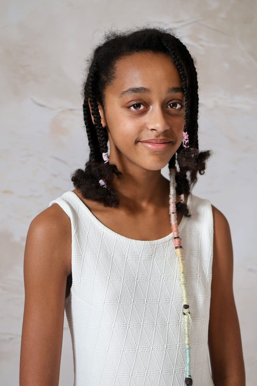 Portrait d’une adolescente aux longues tresses, en robe blanche, au studio.