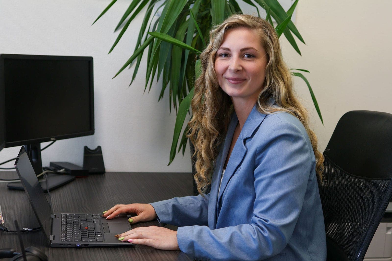 Une conseillère à son poste de travail, sourire vers l’objectif.