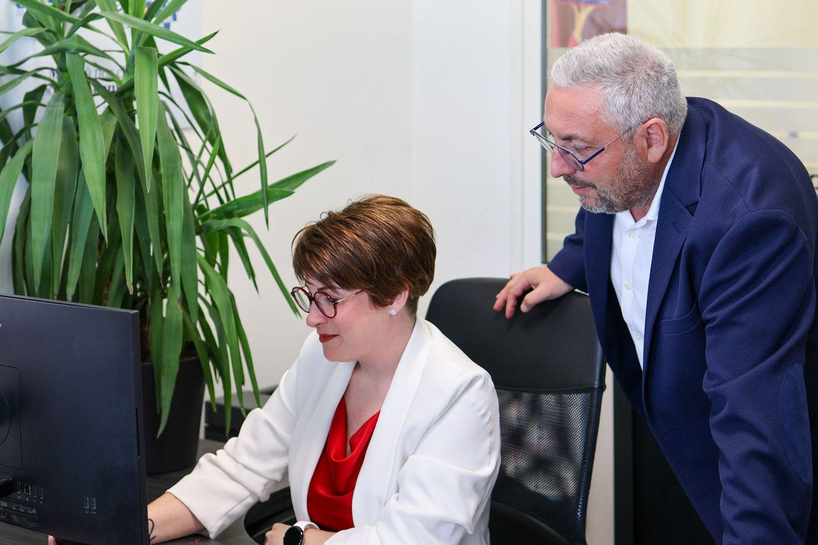 Deux collègues au travail, l’un penché sur l’écran de l’autre.
