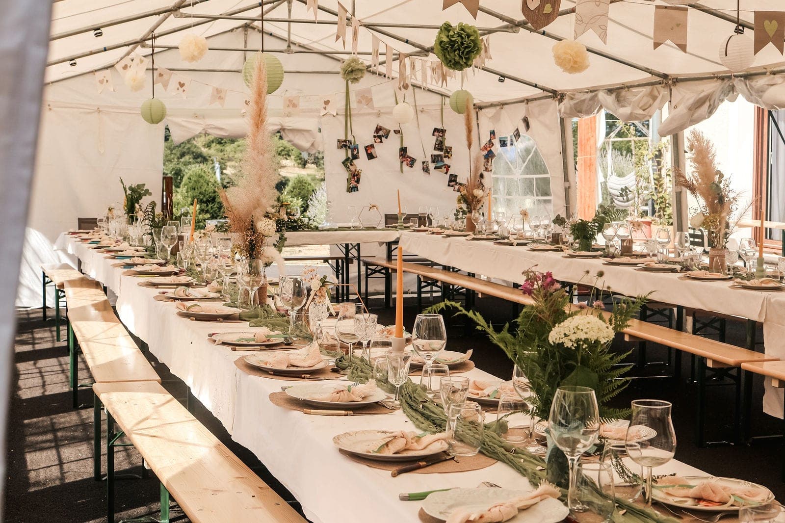 Les tables du repas sous le chapiteau, guirlandes et pampas au plafond.