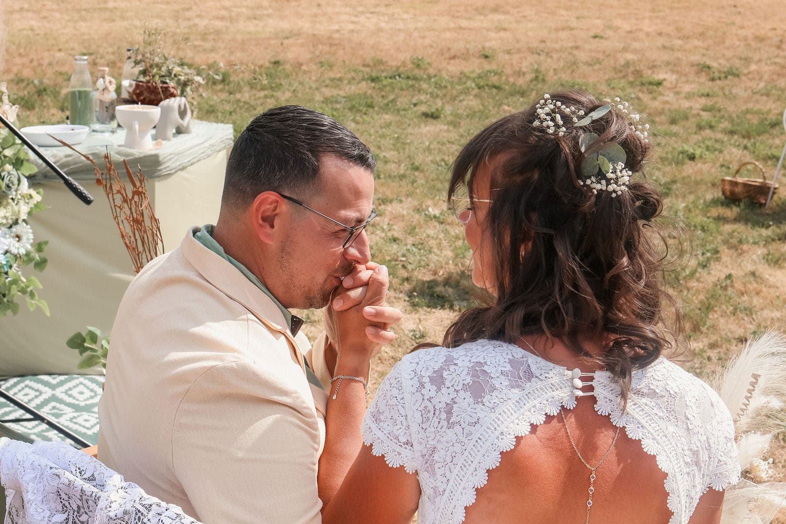 Le marié embrasse la main de la mariée, ému, pendant la cérémonie.
