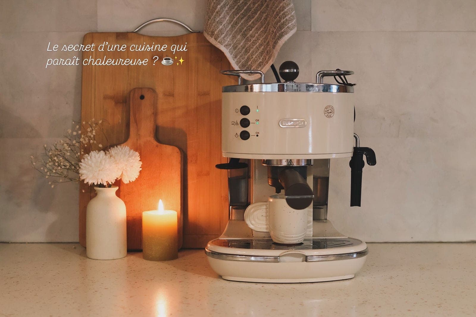 Une machine à café crème mise en scène sur un plan de travail, à la bougie.